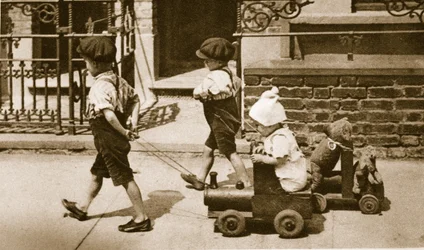 As crianças brincam na rua: meninos puxando carrinhos (foto sépia)